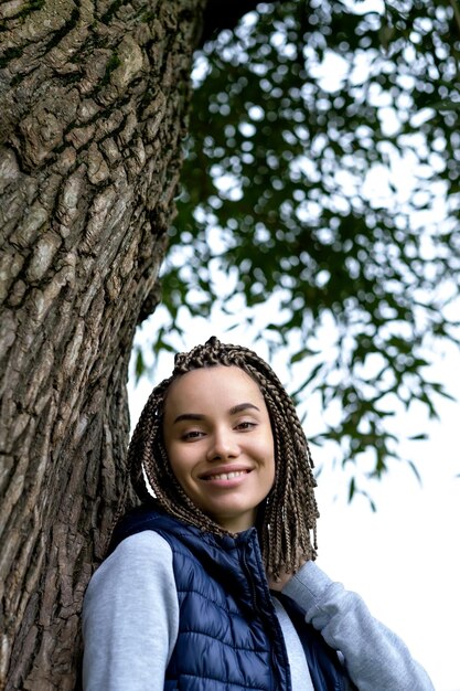 Photo portrait d'une adolescente positive avec des tresses tressées elle sourit largement et regarde avec confiance