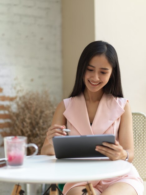 Portrait d'adolescente se détendre avec tablette numérique et boisson sur table basse au café