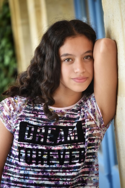 Photo portrait d'une adolescente souriante appuyée sur le mur