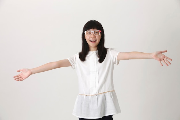 Photo portrait d'une adolescente souriante avec les bras tendus debout sur un fond blanc