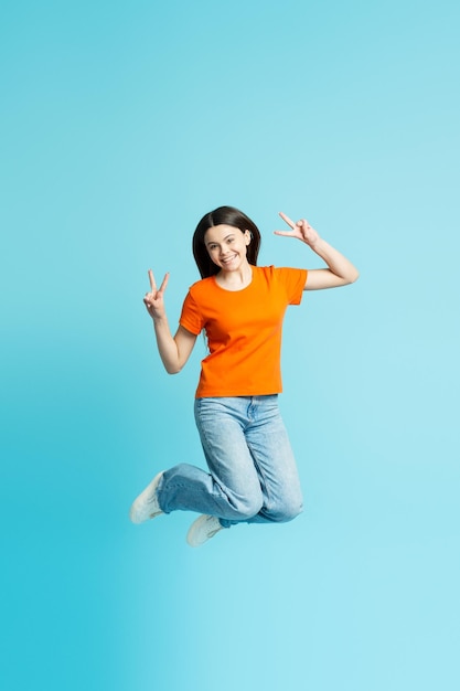 Portrait d'une adolescente souriante et joyeuse sautant des gestes isolés sur fond bleu concept de style de vie heureux