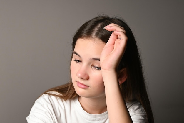 Portrait d'une adolescente triste sur fond gris