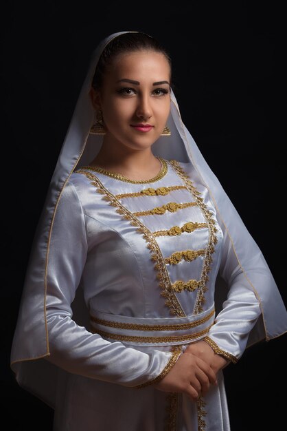 Photo portrait d'une adolescente en vêtements traditionnels sur un fond noir