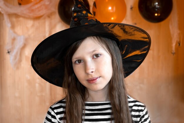 Portrait d'une adorable adolescente portant un chapeau d'Halloween et souriant Petit enfant en costume de sorcière