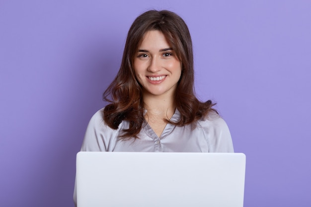 Portrait d'adorable femme souriante tenant un ordinateur portable blanc