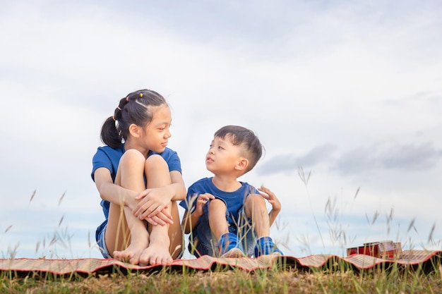 Portrait d'adorable frère et soeur assis à l'extérieur des enfants asiatiques jouant dans le jardin