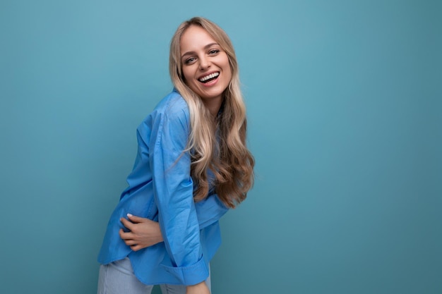 Portrait d'une adorable jeune femme blonde chanceuse sur fond bleu avec un espace vide