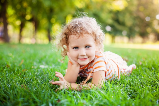 Portrait, de, adorable, petite curle, fille, coucher herbe, et, étayage haut, figure