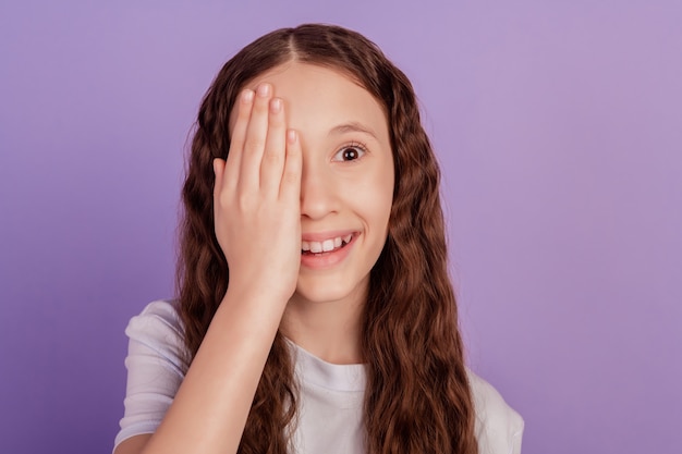 Portrait d'une adorable petite dame douce paume près de la moitié du visage examen de la vue de la caméra sur fond violet