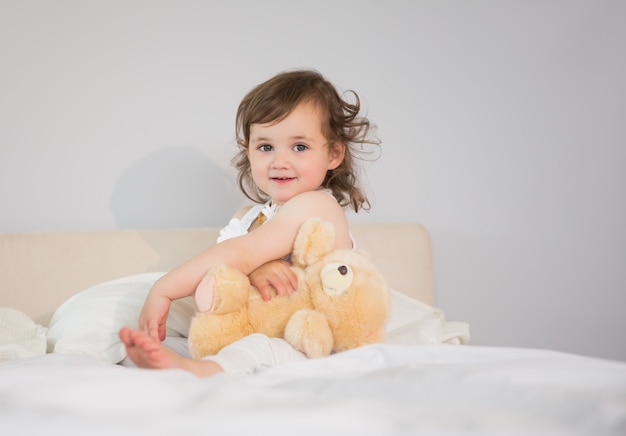 Portrait de l&#39;adorable petite fille assise sur le lit