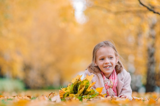 Portrait d'une adorable petite fille avec un bouquet de feuilles jaunes en automne