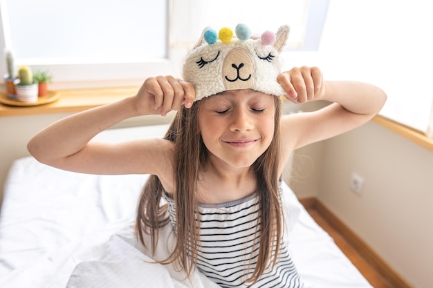 Portrait d'adorable petite fille s'est approchée de son lit le matin ensoleillé