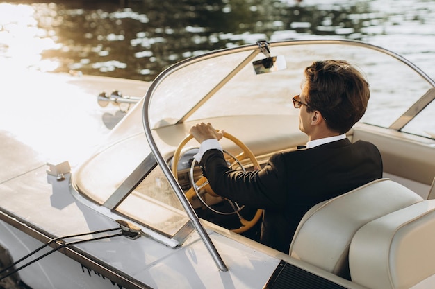 Portrait d'affaires de jeune homme en costume et lunettes de soleil posant sur un yacht