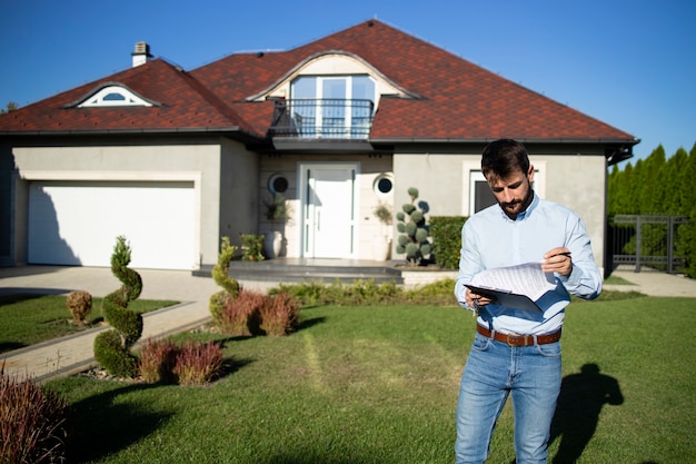 Portrait d'agent immobilier vérifiant le contrat avant que les clients n'arrivent pour acheter la maison