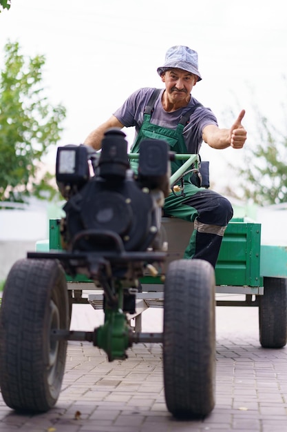 Photo portrait d'agriculteur satisfait assis au volant d'un tracteur à deux roues