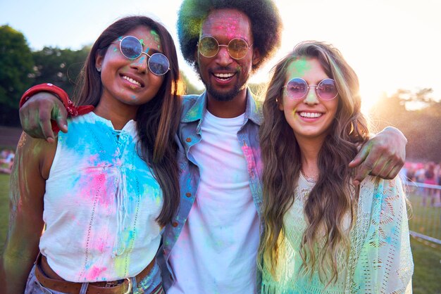 Photo portrait d'amis heureux recouverts de peinture en poudre au carnaval