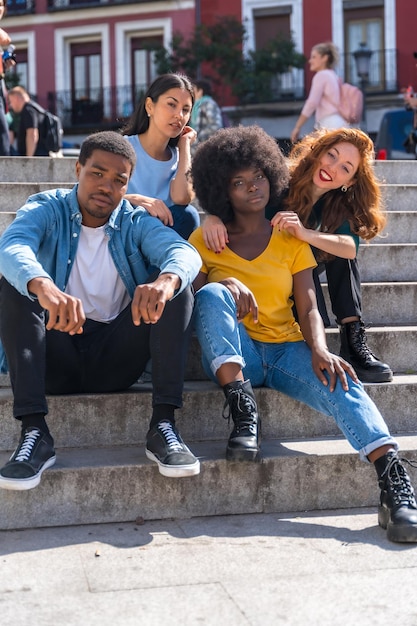 Portrait d'amis multiethniques heureux assis dans les escaliers de la ville jeunes mannequins