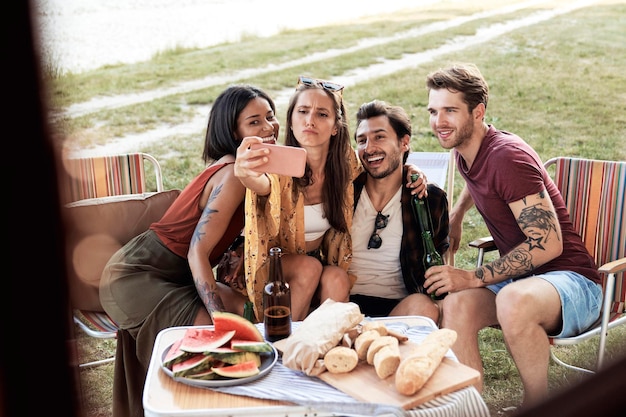 Portrait d'amis souriants qui se font un selfie au camp.