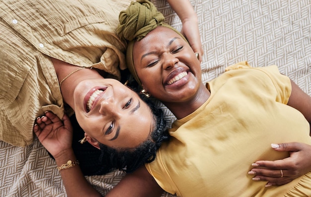 Portrait d'amour LGBT et couple d'amis riant détendez-vous ou souriez pour une blague drôle et profitez du temps à la maison ensemble Humour vue de dessus visage ou partenaire non binaire ou femmes homosexuelles sur le sol