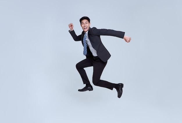 portrait amusant d'un jeune homme d'affaires asiatique énergique et heureux sautant dans les airs sur fond de studio