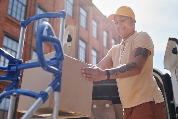 Portrait en angle bas d'une livreuse déchargeant des boîtes en carton dans l'espace de copie de la lumière du soleil