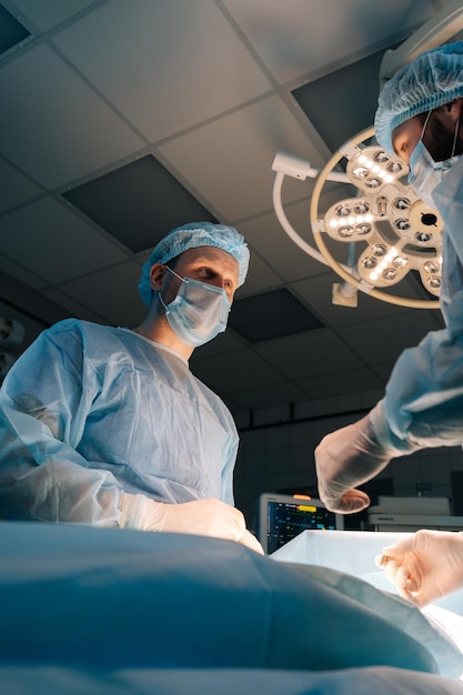 Portrait en angle bas d'un patient chirurgical professionnel opérant des médecins de sexe masculin portant des gants stériles