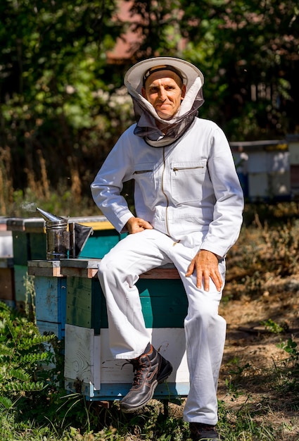 Portrait d'un apiculteur masculin heureux L'apiculteur travaille avec des abeilles et des ruches sur le rucher