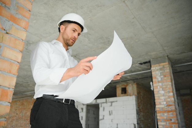 Portrait d'un architecte constructeur étudiant le plan d'aménagement des pièces, ingénieur civil sérieux travaillant avec des documents sur chantier, rénovation de bâtiments et de maisons, contremaître professionnel au travail.