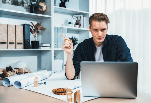 Portrait d'un architecte designer assis au bureau dans un bureau, idée de remue-méninges pour un projet de conception architecturale, rédaction d'un plan avec un ordinateur portable Technologie professionnelle et moderne en architecture Itération