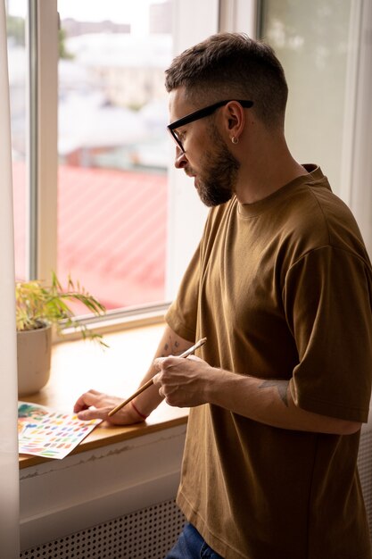 Portrait d'un artiste masculin debout regardant par la fenêtre à la recherche d'inspiration coaching en peinture