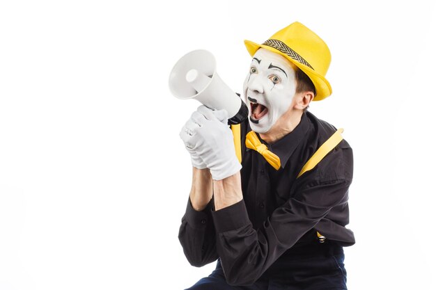 Portrait d'un artiste mime mâle criant ou montrant sur un mégaphone isolé sur fond blanc