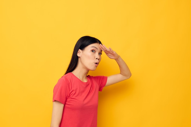 Portrait asiatique belle jeune femme dans un t-shirt rouge posant des émotions fun fond jaune inchangé