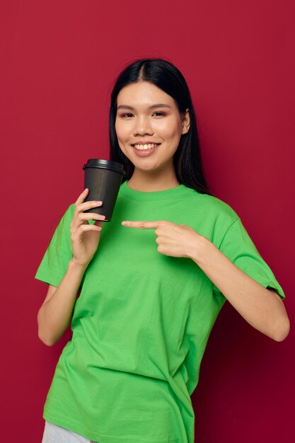 Portrait asiatique belle jeune femme dans un t-shirt vert un verre de boisson amusant fond isolé inchangé