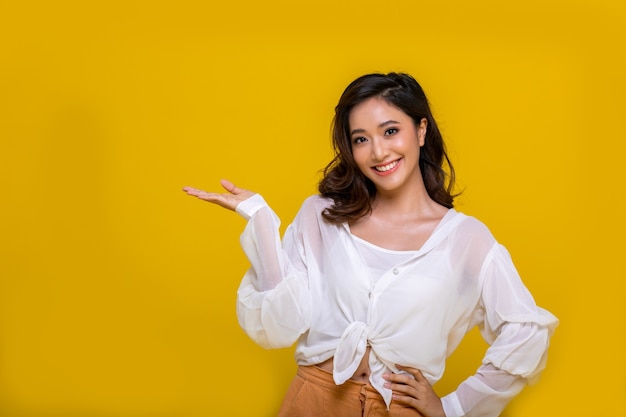 Portrait asiatique belle jeune femme heureuse souriante joyeuse et regardant la caméra isolée sur fond de studio jaune