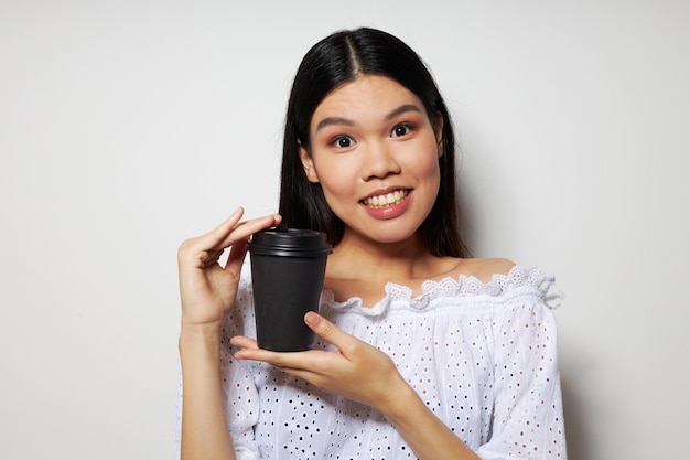 Portrait asiatique belle jeune femme posant avec un verre jetable de boisson amusante fond isolé...