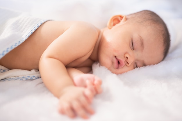 Portrait Asie bébé sur un lit blanc