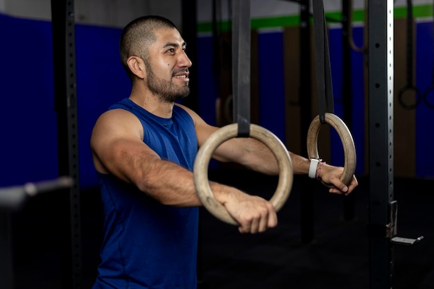 Portrait d'un athlète debout appuyé sur des anneaux de gymnastique sur un site d'entraînement