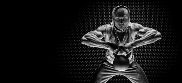 Portrait d'un athlète tirant un kettlebell à son menton. Le concept de sport et de mode de vie sain. Technique mixte