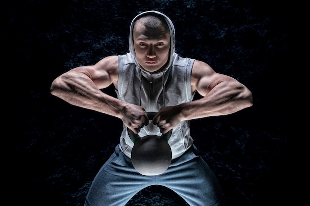 Photo portrait d'un athlète tirant un kettlebell à son menton.