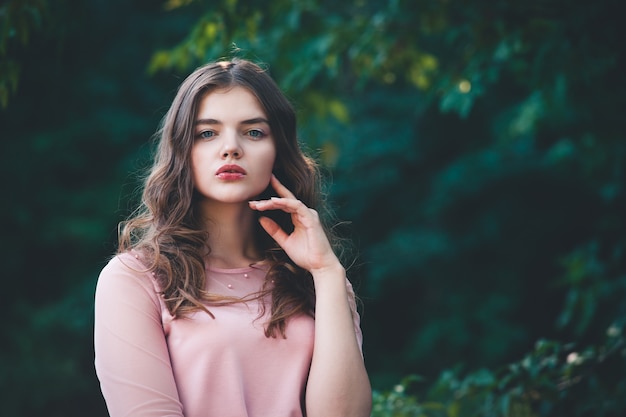 Portrait atmosphérique de la belle jeune femme, cheveux longs et maquillage décontracté, mur de la nature