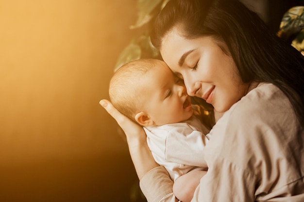 Portrait authentique de la mère et de la fille nouveau-née dans ses bras Une femme se réjouit des câlins et des bisous un enfant parle et réjouit sa fille des sourires heureux sur le visage de la mère et du bébé