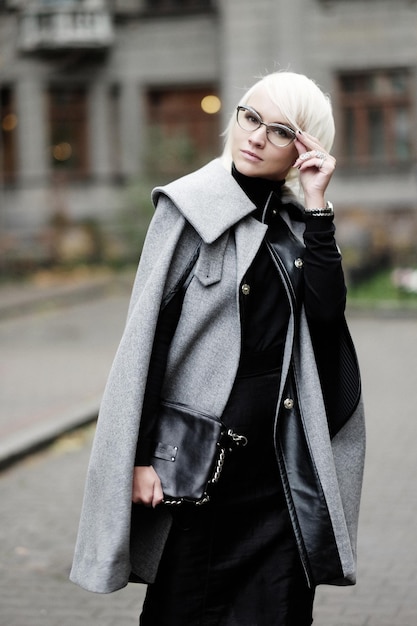 Portrait d'automne de la belle femme blonde en manteau gris avec sac noir