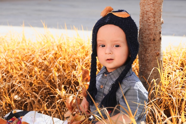 Portrait d'automne d'enfant de 2-3 ans dans le jardin. Automne. Vue rapprochée de joyeux bébé métis doux en bonnet tricoté