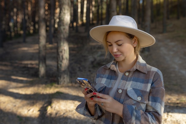 Portrait d'automne d'une femme souriante tenant un téléphone sur le fond de la forêt fille heureuse