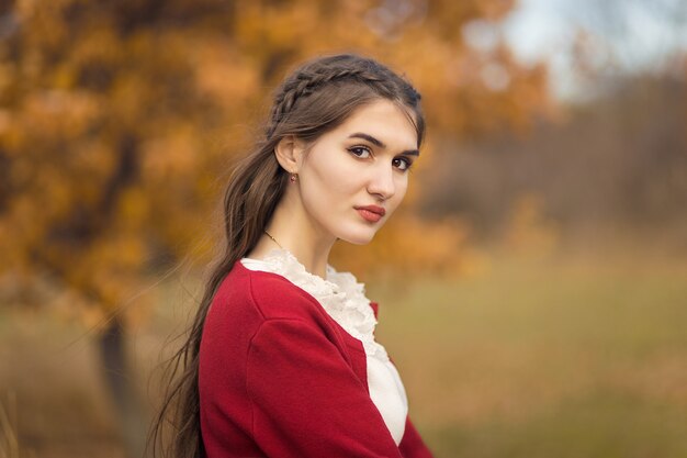 Portrait d'automne d'une fille dans le parc dans un cardigan bordeaux.