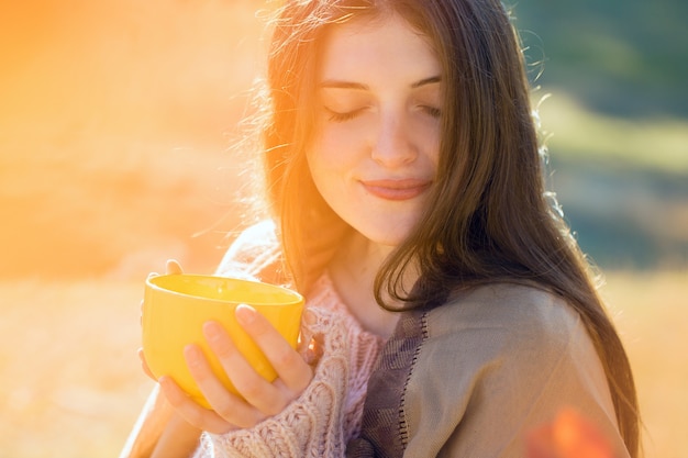 Portrait d'automne d'une fille avec une tasse jaune