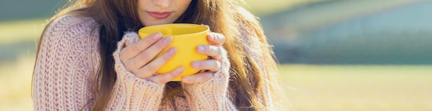 Portrait d'automne d'une fille avec une tasse jaune