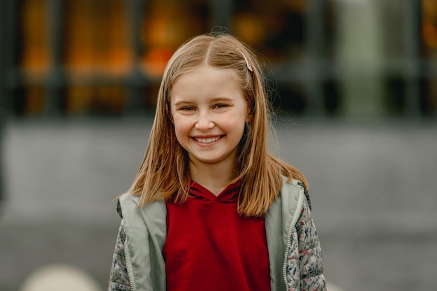 Portrait d'automne de jolie fille enfant à l'extérieur. Enfant de sexe féminin préadolescent regardant la caméra et souriant