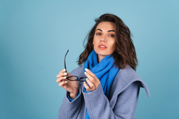 Portrait d'automne de printemps d'une femme dans un chandail tricoté bleu, une écharpe et un manteau gris, posant à la mode, en prévision du printemps