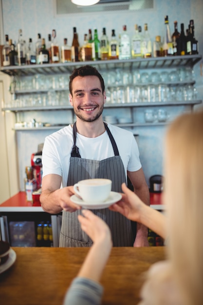 Portrait de barista confiant servant du café au client au café